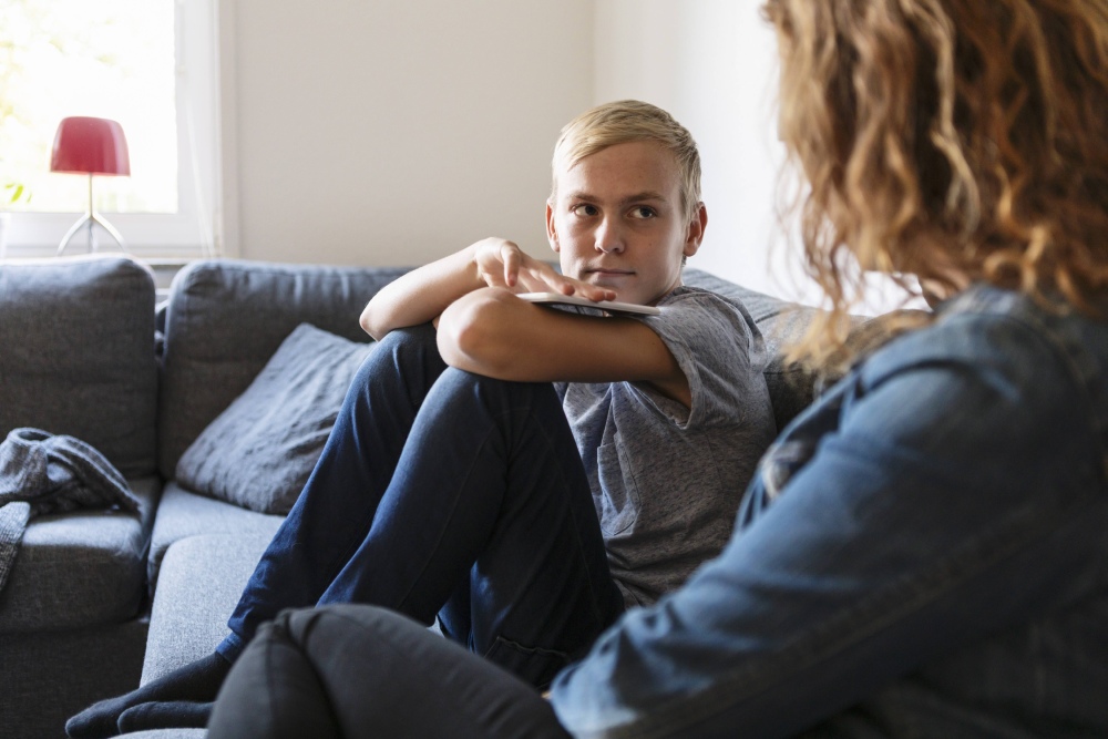 Young boy sitting on sofa looking at adult female